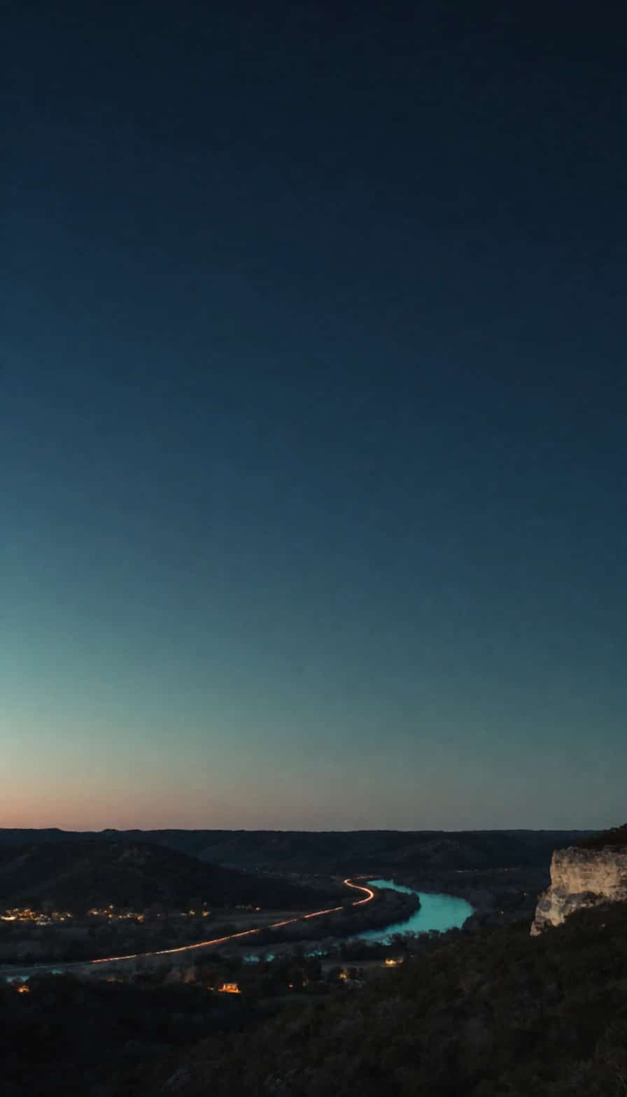 A river valley at blue hour with small-town lights below a limestone bluff.