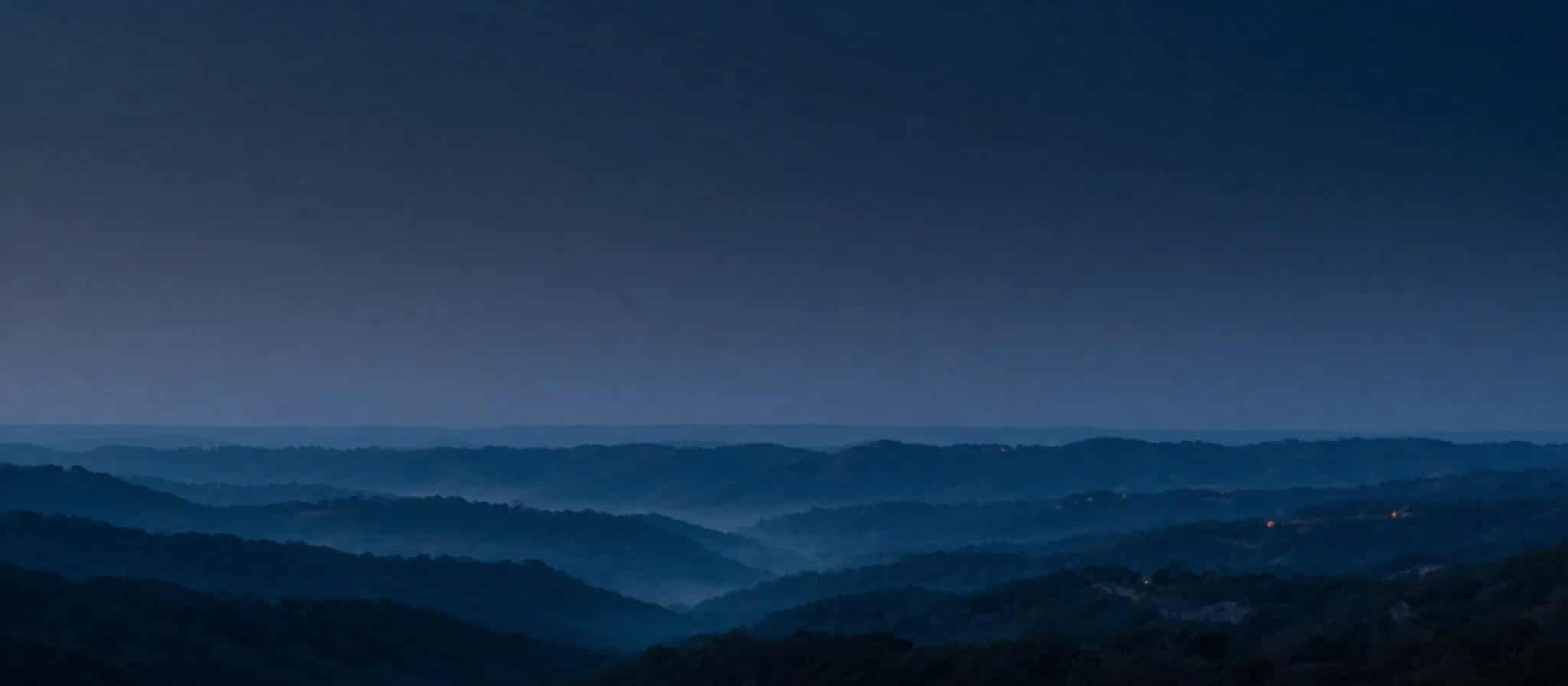 Layered ridgelines fading into blue-hour haze.